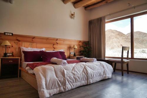 a bedroom with a large bed and a large window at The Hermit Homestay in Leh
