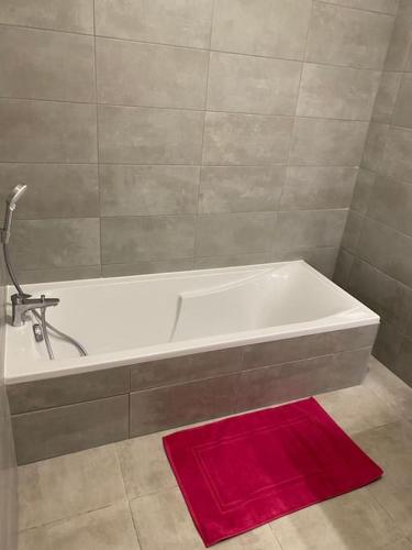 La salle de bains est pourvue d'une baignoire avec un tapis rouge. dans l'établissement Superbe appartement sur les hauteurs d’Ajaccio, à Ajaccio