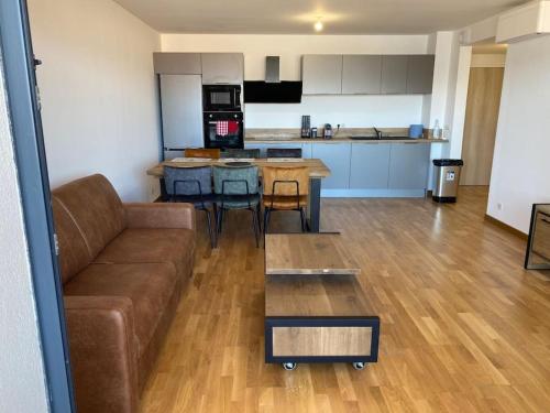 un salon avec un canapé et une cuisine dans l'établissement Superbe appartement sur les hauteurs d’Ajaccio, à Ajaccio