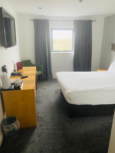 a hotel room with a bed and a desk and a television at Ramada Birmingham Oldbury M5 J2 in Oldbury