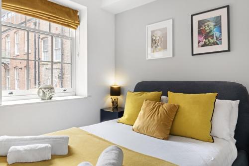 um quarto com uma cama com almofadas amarelas e uma janela em Luxury 1 Bedroom Lace Market Apartment em Nottingham