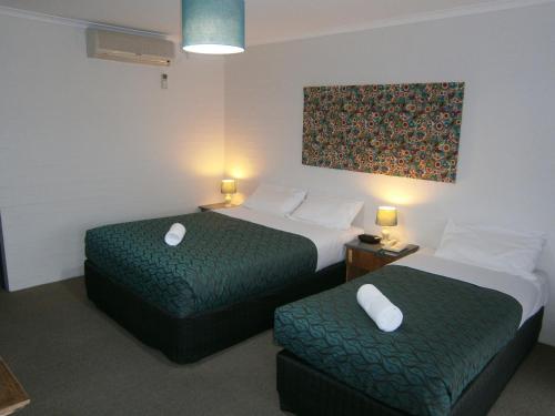 a hotel room with two beds and a painting on the wall at Winsor Park Motor Inn in Albury
