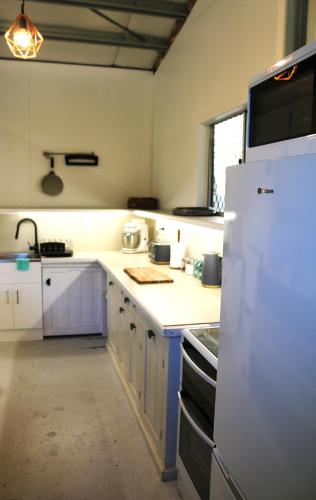 a kitchen with purple cabinets and a white refrigerator at Beach Shed with Pizza Oven in Toogoom