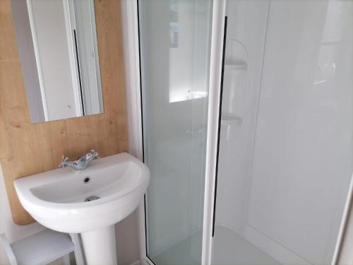 a white bathroom with a sink and a shower at The Beach - Large decking area in Kent