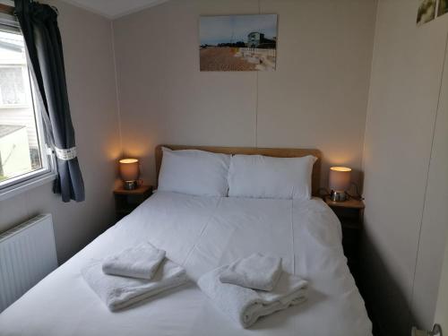 a bedroom with a white bed with towels on it at The Beach - Large decking area in Kent
