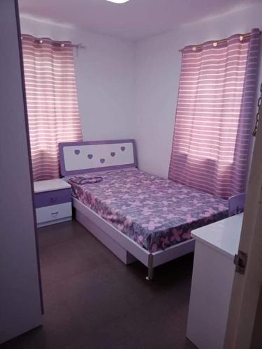 ein kleines Schlafzimmer mit einem Bett und zwei Fenstern in der Unterkunft Al Manzil in General Santos