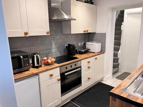 a kitchen with white cabinets and a stove top oven at Meadow Street Rooms in Avonmouth