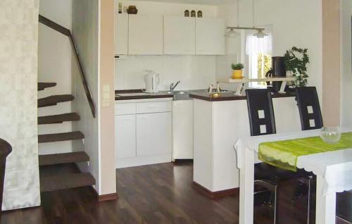 una cocina con armarios blancos, una mesa y una escalera en 2 Bedroom Pet Friendly Home In Plau Am See, en Plau am See