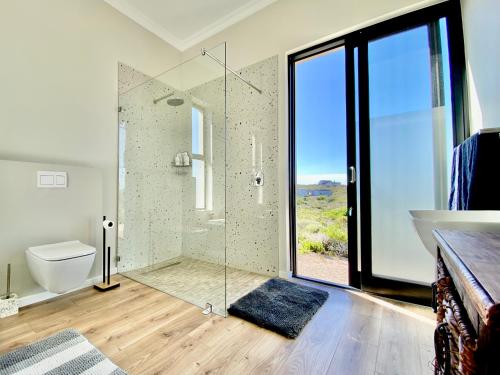 a bathroom with a glass shower and a toilet at Lighthouse Villa Romansbaai in Gansbaai