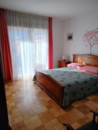 a bedroom with a bed and a large window at Appartamento Alla Vigna in Levico Terme