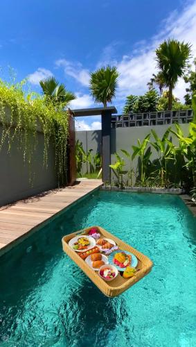 a tray of food on a board in a swimming pool at The Clifton Canggu in Canggu
