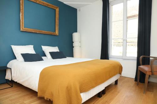 a bedroom with a large bed with a yellow blanket on it at Suite Lavarande by La Boîte En Plus in Senlis