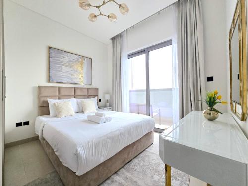 a white bedroom with a bed and a glass table at Sleek and Stylish 2-Bedroom Apartment in Dubai