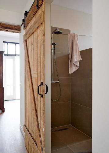 a sliding barn door opens to a shower in a bathroom at La Dominotte Arcen in Arcen