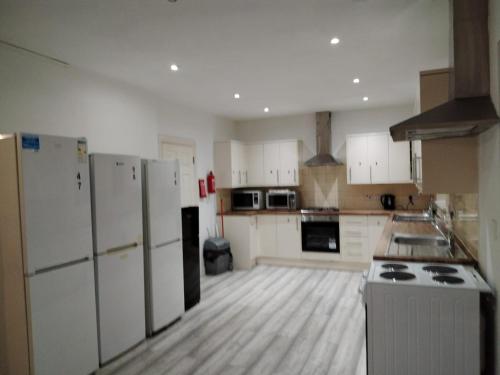 a large kitchen with white appliances and wooden floors at Large Double Room Private Bathroom And SmartTV 8 in Barking