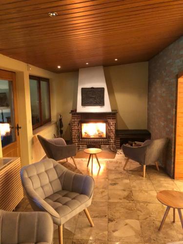 a living room with a fireplace and a couch and chairs at Das Schwarzwaldhotel in Todtmoos