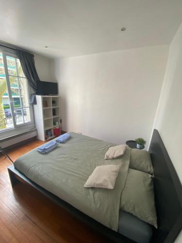 Una cama grande en un dormitorio con una ventana grande. en Studio Proche Paris, en Chaville