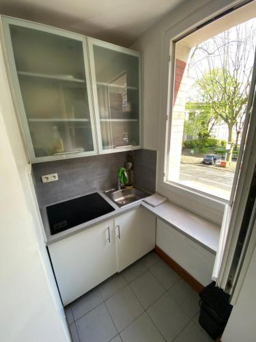 une petite cuisine avec un évier et une fenêtre dans l'établissement Studio Proche Paris, à Chaville