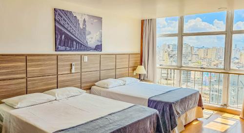 a hotel room with two beds and a large window at Hotel Dan Inn Planalto São Paulo in Sao Paulo