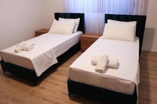 two beds in a hotel room with towels on them at Albora Guest House in Fier