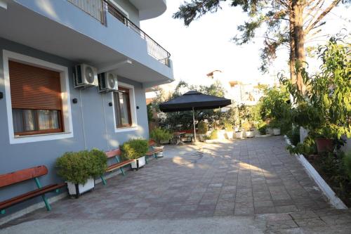 un patio con bancos y una sombrilla junto a un edificio en Albora Guest House en Fier