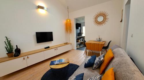 a living room with a couch and a television at Les Appartements du 104 in Saint-Jean-de-Monts