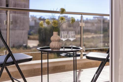 a table with two glasses and a vase with flowers at Your overseas home in MALTA! in Żabbar