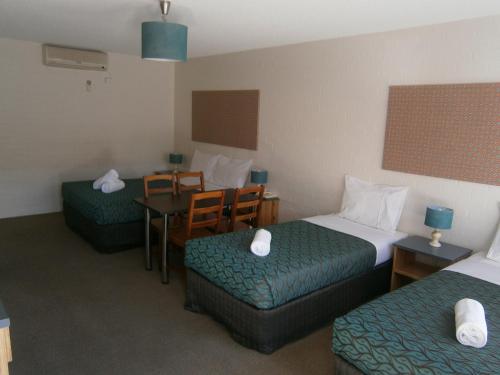 a hotel room with two beds and a table and chairs at Winsor Park Motor Inn in Albury