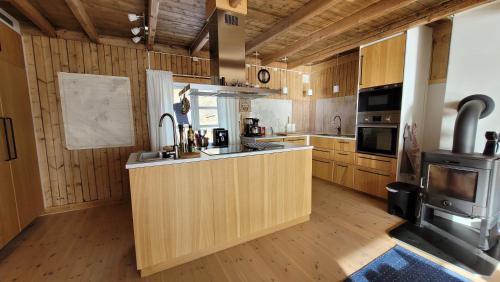 a kitchen with wooden cabinets and a stove at Solodden, Authentic rorbu in Lofoten in Sennesvik