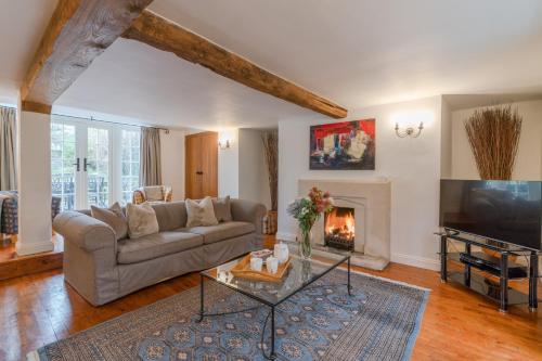 a living room with a couch and a fireplace at Cotswold Cottage in Cirencester
