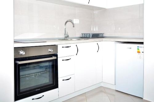 een witte keuken met een wastafel en een magnetron bij Laki in Nikšić