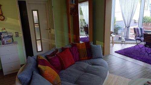 a living room with a blue couch with colorful pillows at Ferienhaus Rose & Lavendel in Zühlsdorf