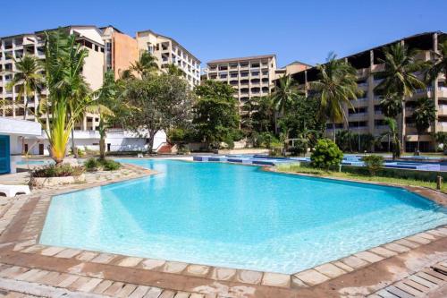 a large swimming pool with buildings in the background at Imani Front Beach Appartment in Diani Beach