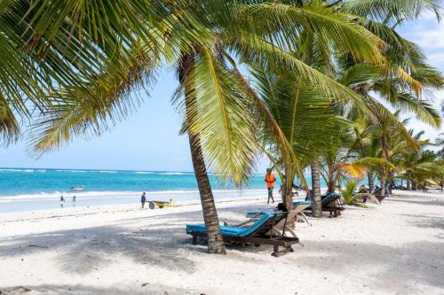 a beach with palm trees and people on the beach at Imani Front Beach Appartment in Diani Beach