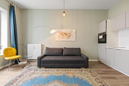 a living room with a couch and a yellow chair at primeflats - Apartment Langhans Berlin-Weißensee in Berlin