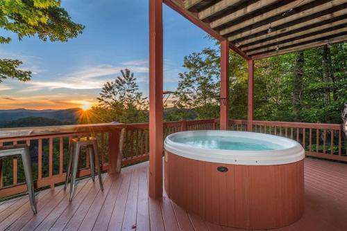 a hot tub on a deck with the sunset at The Skybox Cabin Stunning Views HotTub Game Room in Swiss