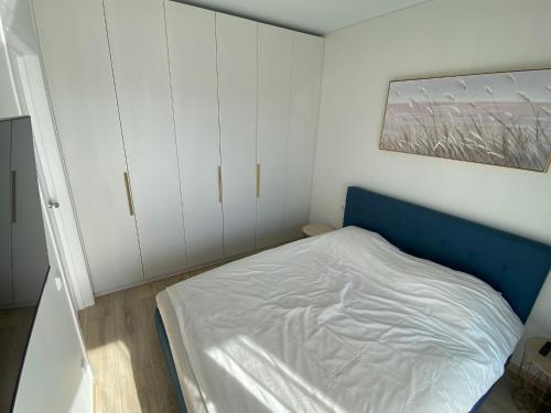a small bedroom with a bed and white cabinets at Laiminga banga in Palanga