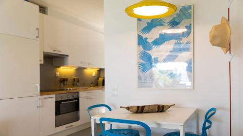 cocina con mesa blanca y sillas azules en Villa Sand and Sea, en Pelekas