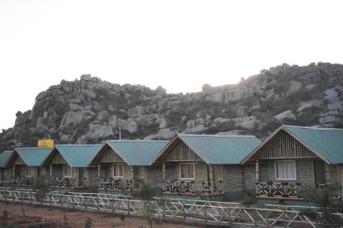 a row of wooden houses with a mountain in the background at Mowgli's Cafe Hampi & Guest House in Hampi