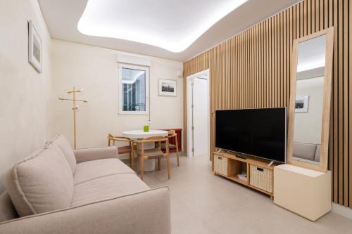 ein Wohnzimmer mit einem Sofa und einem TV in der Unterkunft apartamento exclusivo en el retiro METRO IBIZA in Madrid