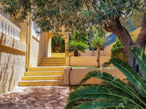 une maison jaune avec des escaliers, des arbres et des plantes dans l'établissement Villa de 2 plantas, à Oropesa del Mar