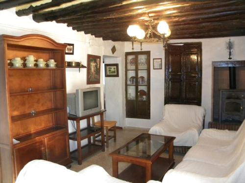 sala de estar con sofá y TV en Cortijo Pulgarín Bajo en Alfarnatejo