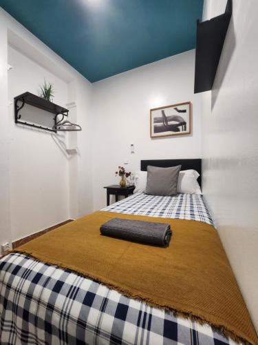 Un dormitorio con una cama con una manta. en M-A Catrachos Rooms, en Madrid
