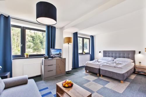 - une chambre avec un lit, une télévision et un canapé dans l'établissement Hotel Zerrenpach Látky, à Látky