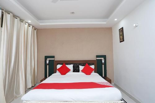 1 dormitorio con 1 cama grande con almohadas rojas en Super Capital O Hotel Levanti Near Aravali Biodiversity Park, en Gurgaon