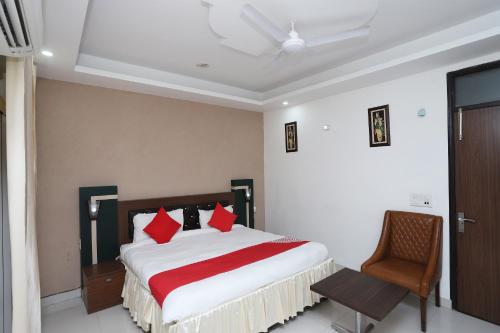 Un dormitorio con una cama con almohadas rojas y una silla en Super Capital O Hotel Levanti Near Aravali Biodiversity Park, en Gurgaon