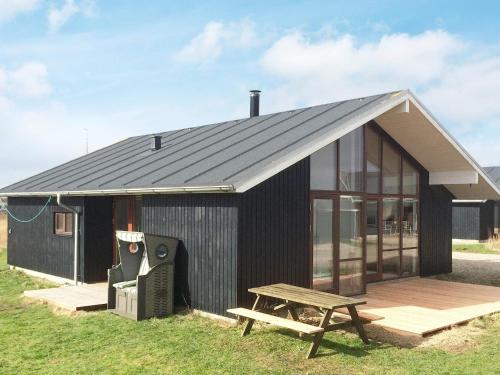 ein schwarzes Haus mit einem Picknicktisch und einer Bank in der Unterkunft 7 person holiday home in Ulfborg in Thorsminde