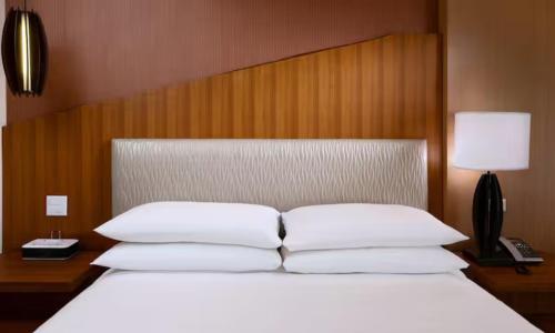 a bed with white pillows and a wooden headboard at The Inverness Denver, a Hilton Golf & Spa Resort in Englewood