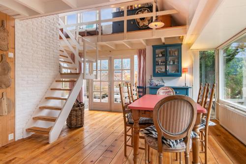 a dining room with a table and a spiral staircase at Het Zeepaartje, knus en gezellig in Noordwijkerhout