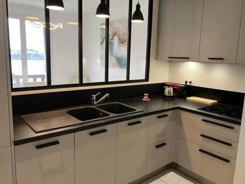 une cuisine avec des armoires blanches et un évier dans l'établissement Les Pieds dans l'Eau, à Donville-les-Bains